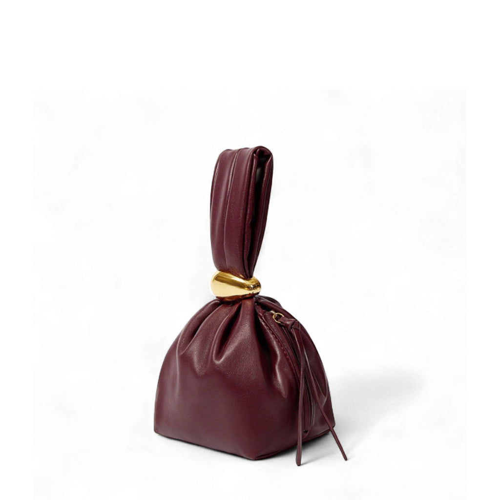 Burgundy faux leather knot handbag with gathered drawstring closure. Sculpted evening clutch or wristlet bag.